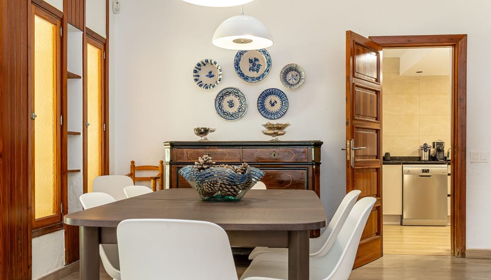 Dining room with wooden table, white chairs and direct access to the kitchen