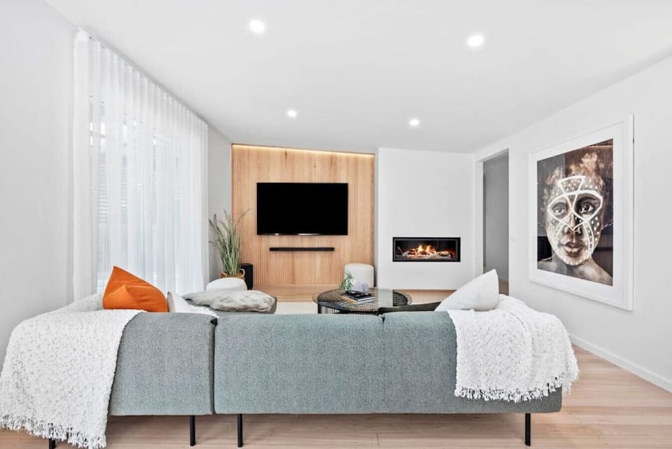 Unwind in this stylish living room with a plush lounge, modern fireplace, large TV, and curated art creating a warm, contemporary vibe