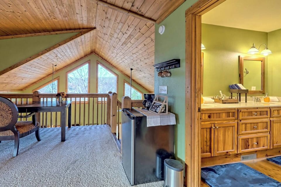 mini fridge in loft area with a desk seated overlooking the living area with a wall of windows