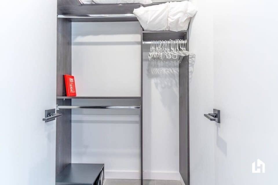Spacious walk-in closet with ample hangers, shelving, and extra pillows.