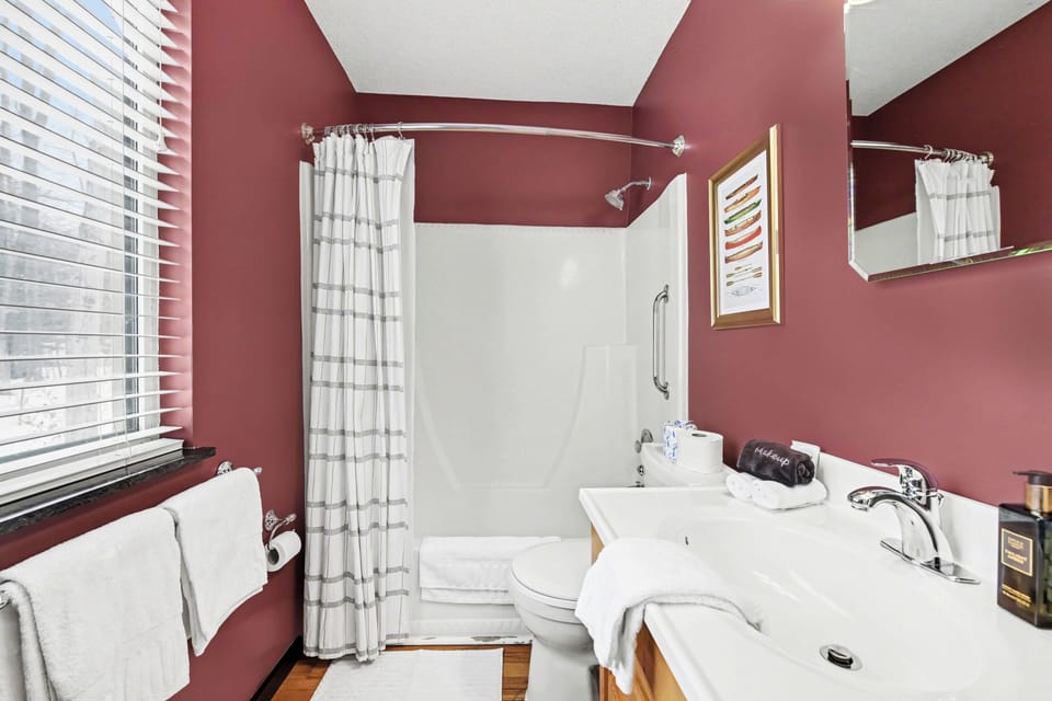 Bathroom vanity and tub shower with window at Sugarloaf Chalet in Arcadia, Michigan