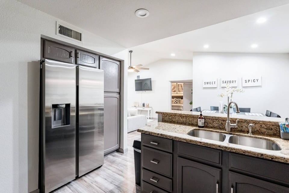 Cook and connect in a bright modern kitchen featuring stainless steel appliances, granite counters, and an open dining area.