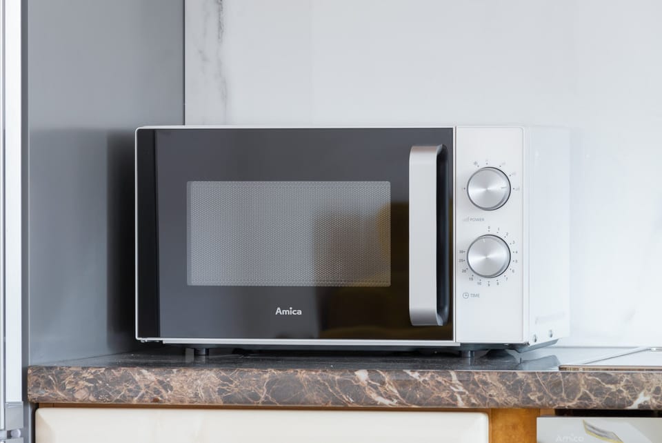 A functional corner of the kitchen showcasing the microwave setup and additional storage.
