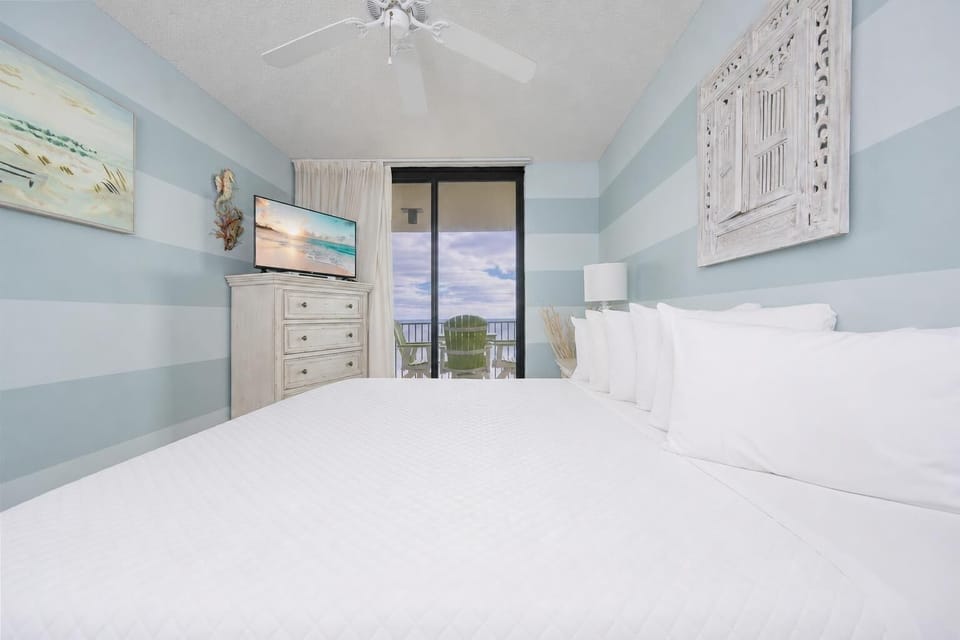 Gentle light fills the master suite as you relax on crisp white bedding with a calming striped wall backdrop