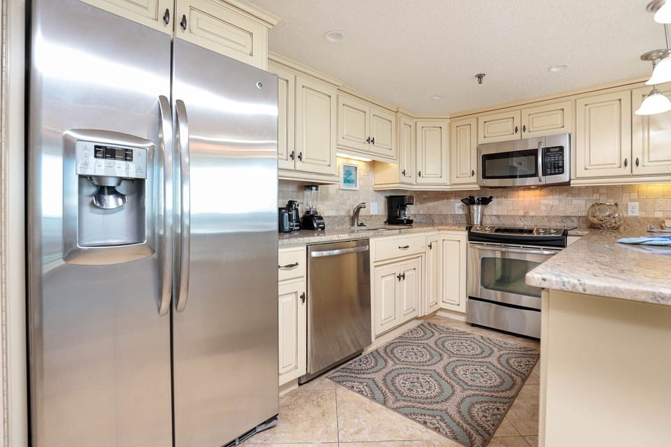 The kitchen features cream cabinetry, granite countertops, stainless appliances, and a decorative area rug for added charm