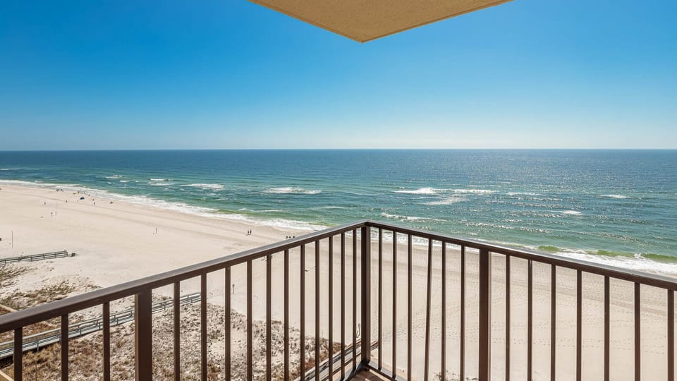 The balcony offers a panoramic view of the sparkling water and white sand beach, inviting relaxation and enjoyment
