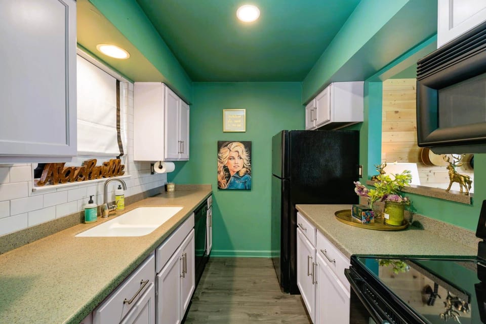 An inviting kitchen featuring trendy green walls contrasted with sleek black appliances, creating a modern and stylish ambiance. 🌿 #KitchenGoals