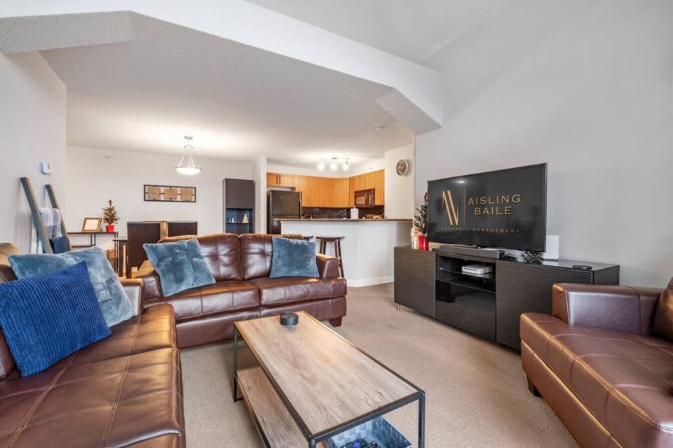 Living room with a Smart TV, walkout access to the top-floor balcony and cozy seating options with a queen pull-out couch (all bedding provided.)