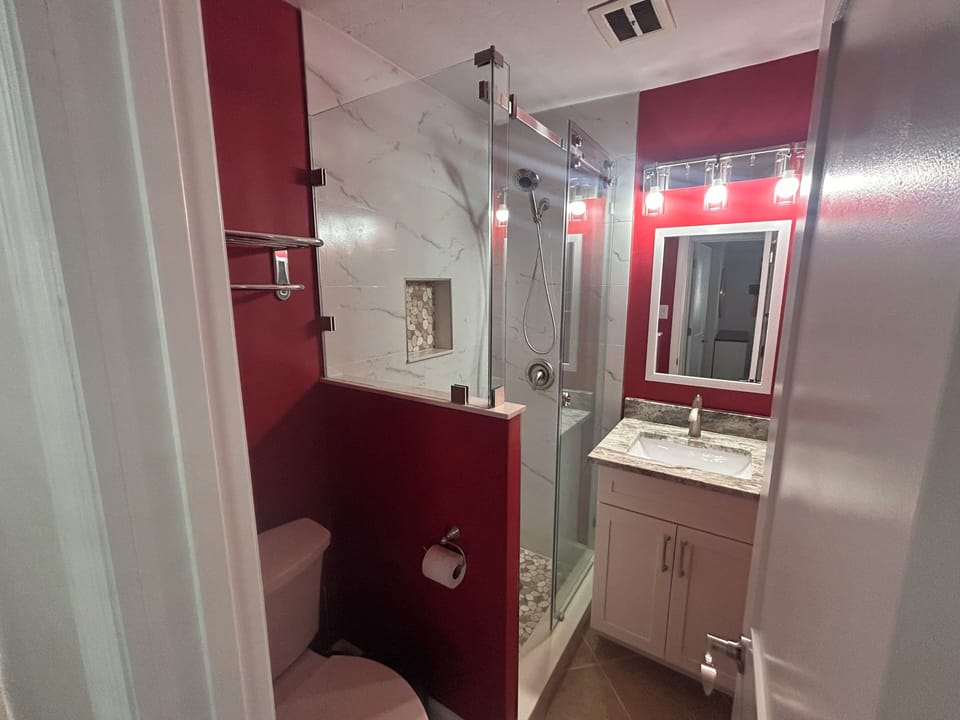 Refresh in your modern bathroom featuring a spacious glass shower, elegant marble accents, and stylish red design touches.