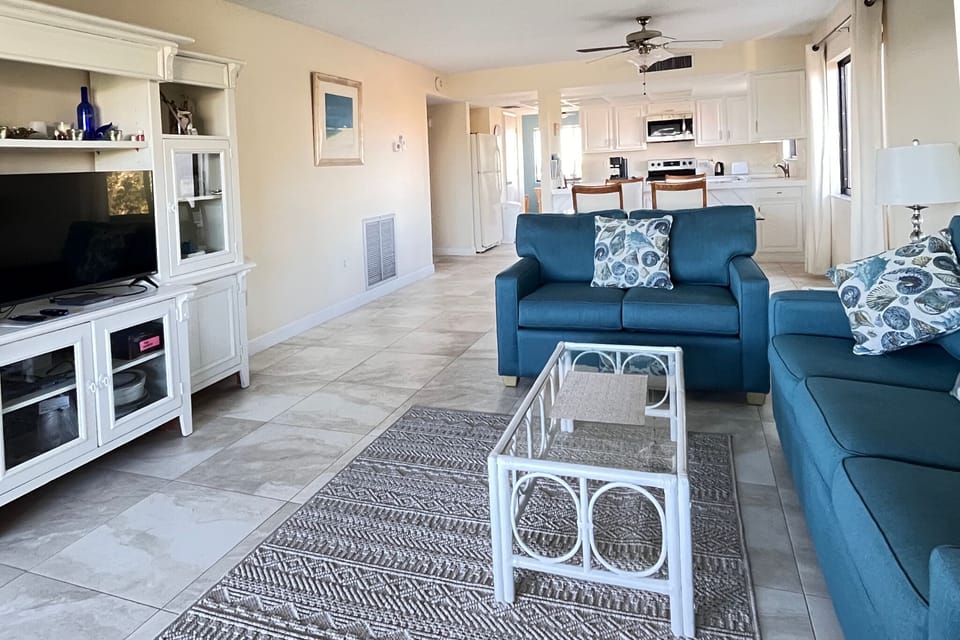 Sink into plush blue seating and enjoy your favorite shows on the large TV in this bright, airy living space that flows seamlessly into the modern kitchen.