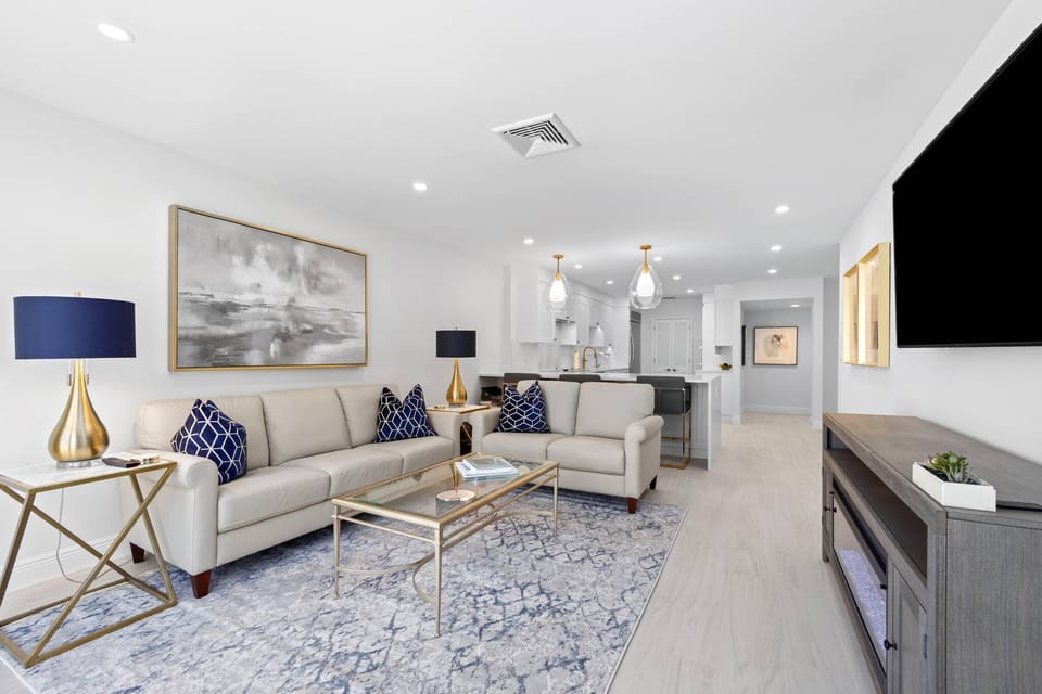 Second family room near kitchen with balcony and large table outside with shade.