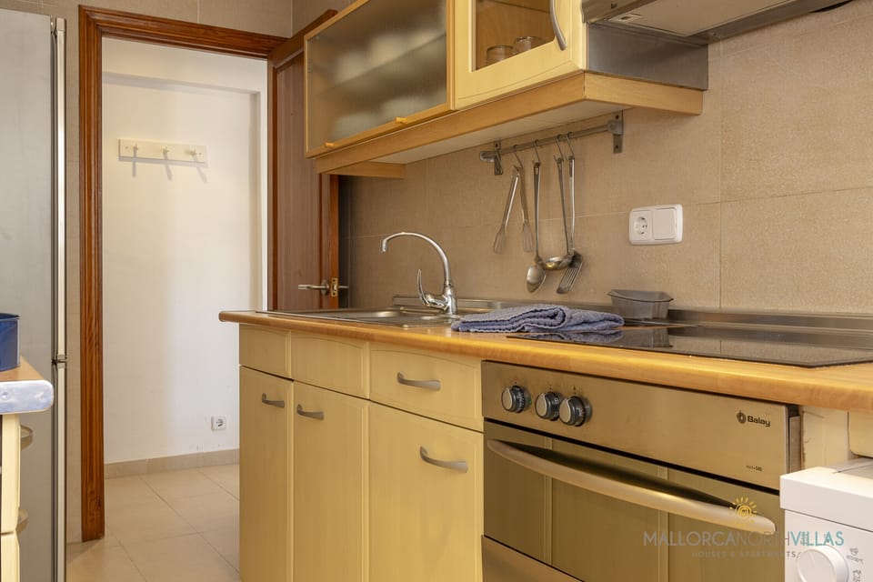Kitchen with oven, hanging utensils and wooden countertop.
