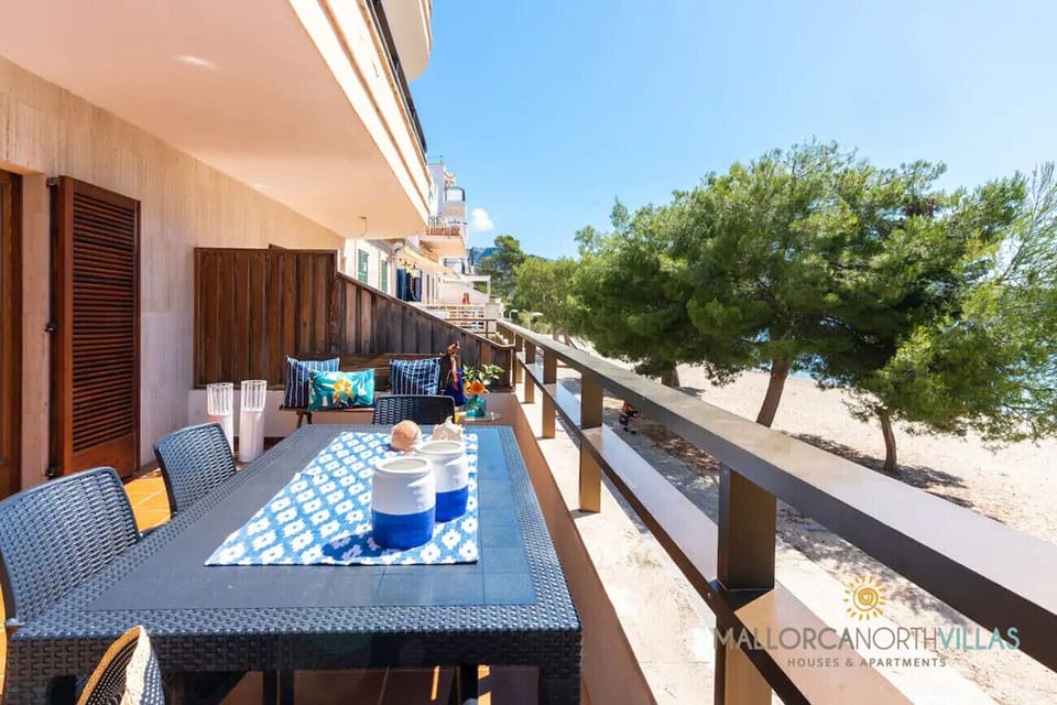 Spacious seafront terrace in Puerto de Pollensa, Mallorca, with table and chairs to enjoy outdoor dining.