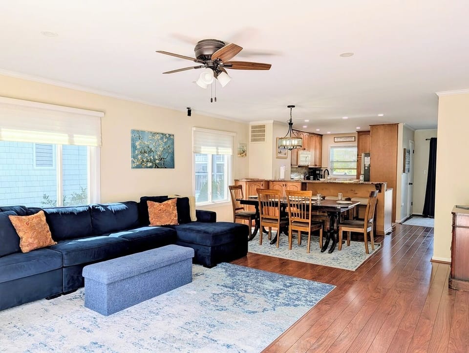 39562 Admiral Road, Tower Shores, North Bethany - open concept - A spacious and bright family room featuring a navy blue sectional sofa and a modern fireplace, offering a perfect setting for coastal relaxation.