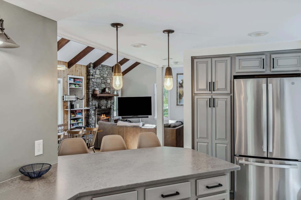 Kitchen island with pendant lighting, stainless refrigerator, and open view to the living room
