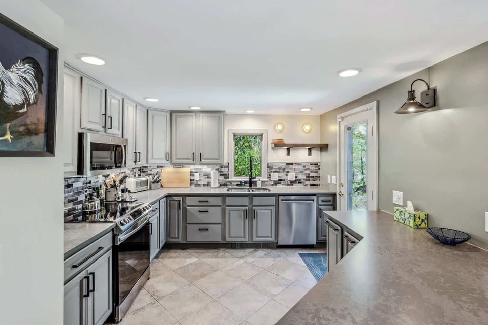 Renovated kitchen with stainless steel appliances, tile backsplash, and quartz countertops