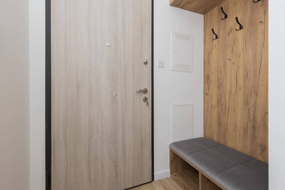The apartment’s entryway has wooden cabinetry and a small bench. The space is functional with plenty of storage and seating options.