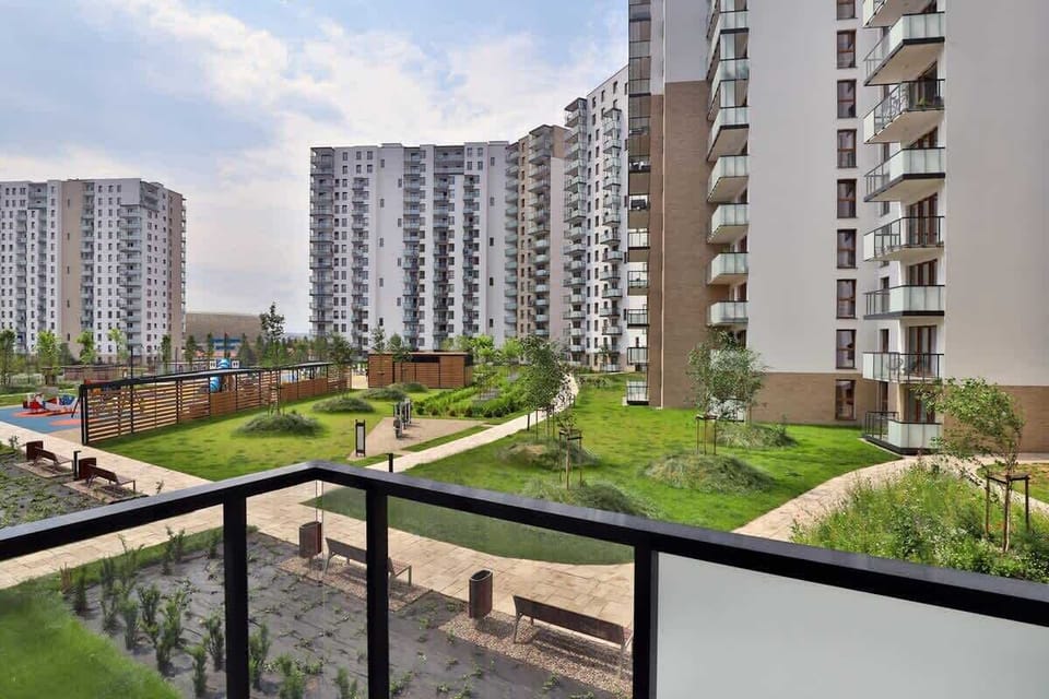 A scenic view of a modern residential complex with high-rise buildings and green spaces below, showcasing urban living with ample greenery.