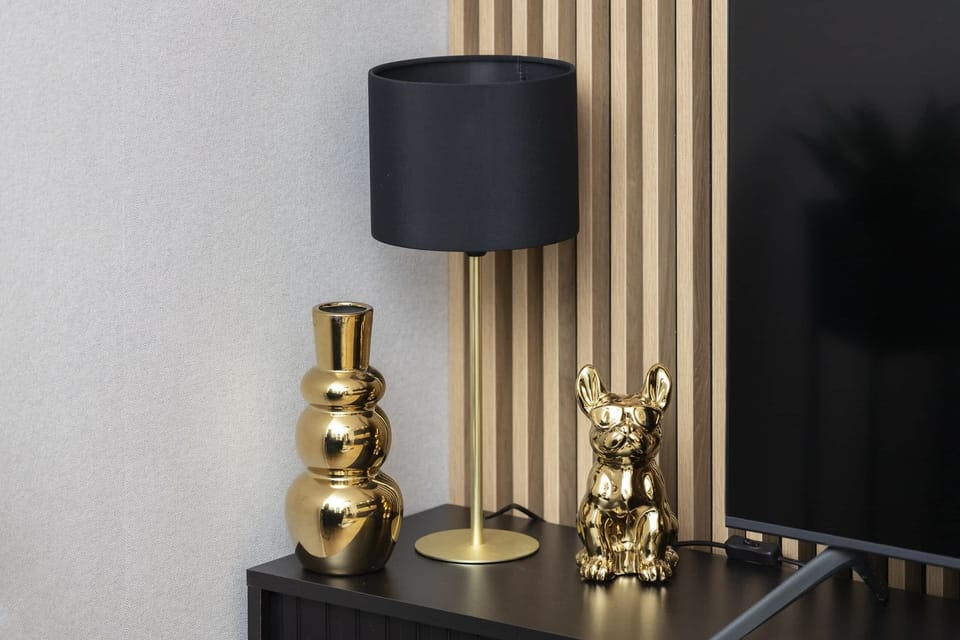A close-up of a small black table with gold-accented decorations, including a lamp and a figurine.