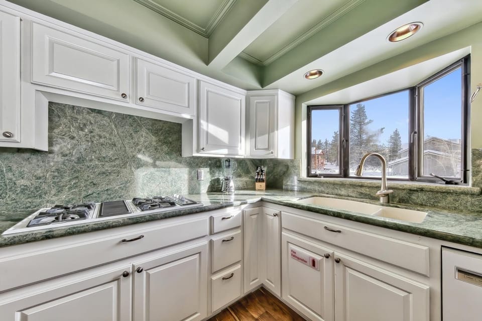 Cook with mountain views through your bright kitchen windows, featuring elegant granite countertops and crisp white cabinetry.