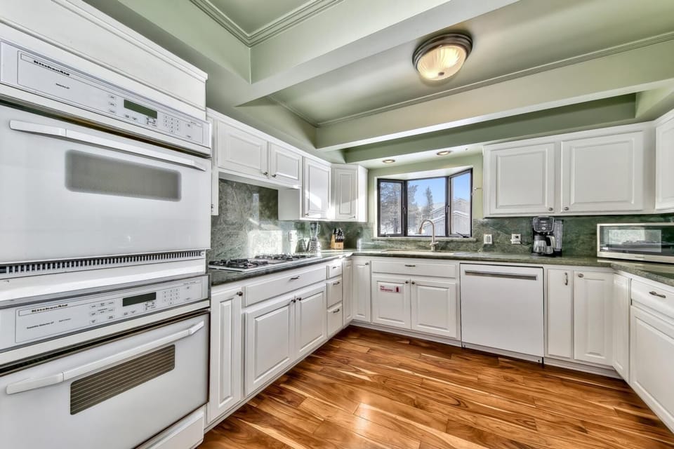You'll love preparing meals in this spacious kitchen featuring granite countertops, white cabinetry, and gleaming hardwood floors beneath elegant coffered ceilings.