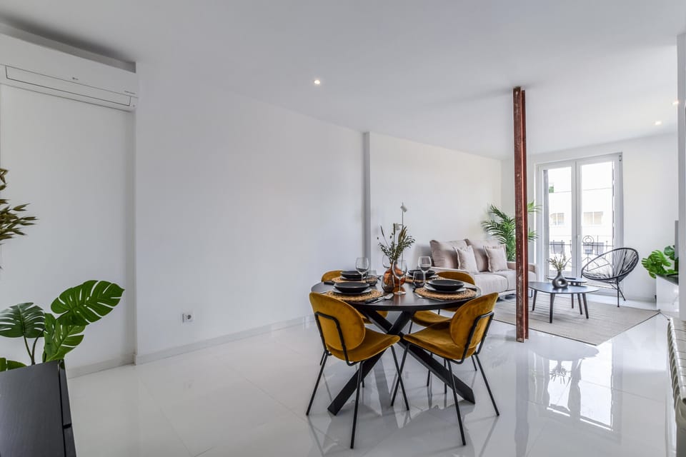 Main view of the dining area with a round wooden table for 4 people with the living room in the background