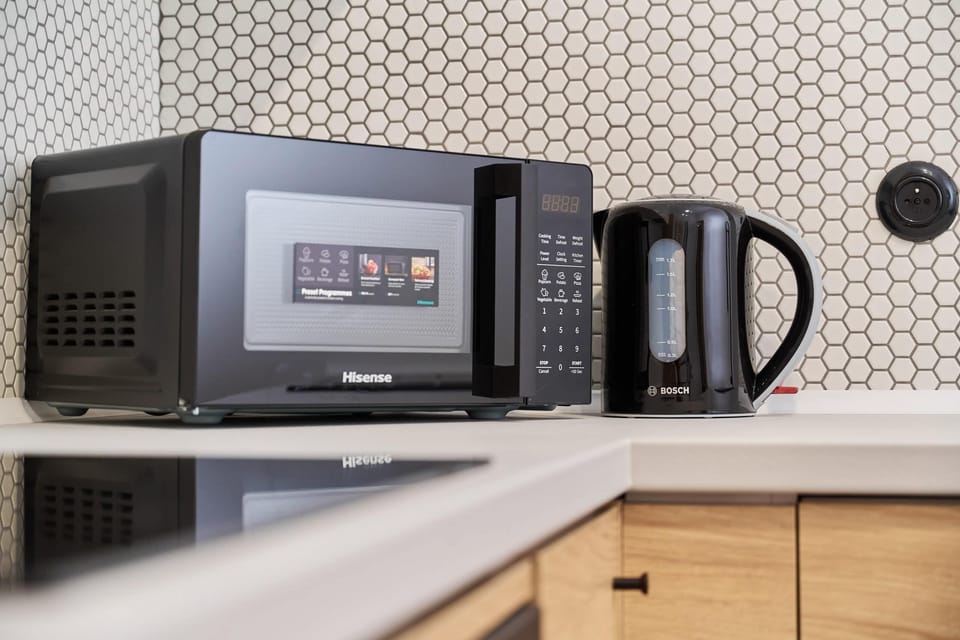 A closer look at a kitchen area featuring a microwave, kettle, and toaster neatly placed on the counter.