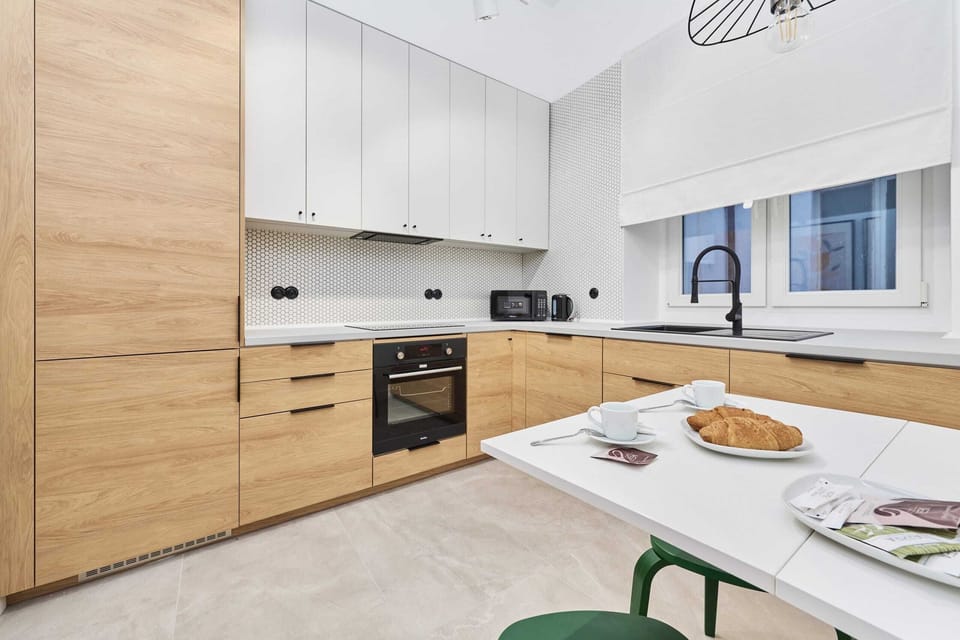 A sleek kitchen with wooden countertops, white cabinets, and a patterned backsplash, offering a modern and functional design.