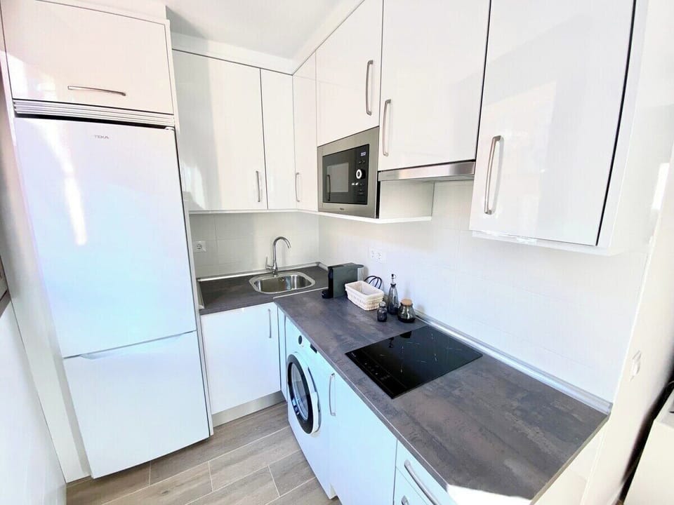 Cocina equipada con frigorífico, lavadora, vitrocerámica, microondas y fregadero. / Kitchen equipped with fridge, washing machine, microwave, ceramic stove, microwave and sink.