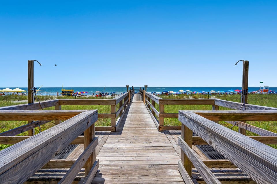 Wooden boardwalk out to the beach umbrellas at Springs Towers 705, a 3-bedroom Cherry Grove condo