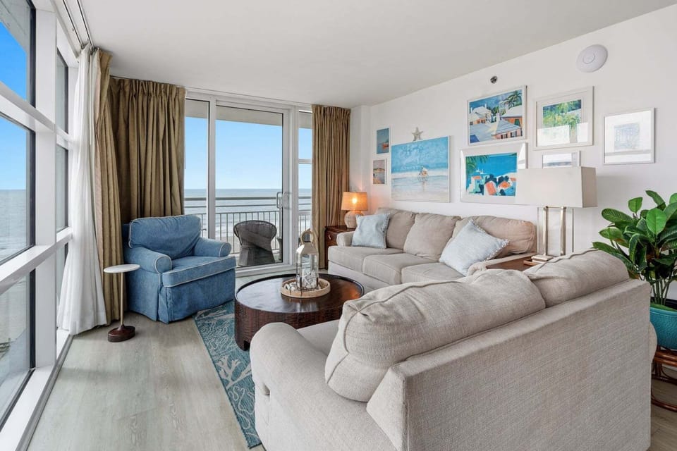 Sectional sofa and blue armchair by the balcony doors at Seaside Resort 503 in Crescent Beach, North Myrtle Beach