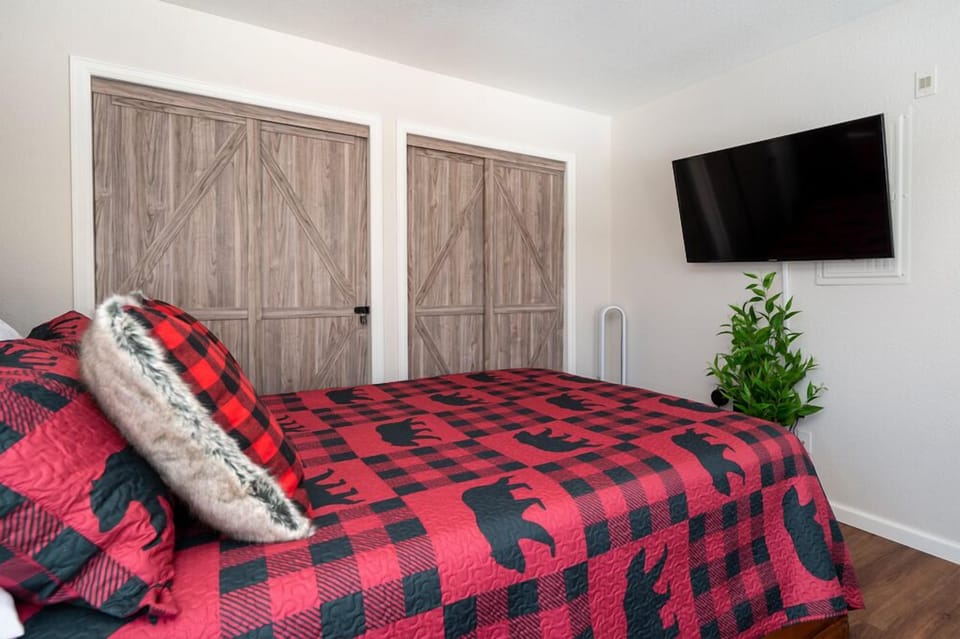 Cozy up in your rustic bedroom with plaid bedding, barn doors, and entertainment ready for relaxing evenings.