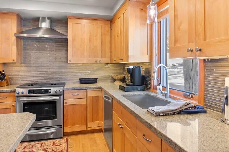 The fully equipped kitchen has stainless steel appliances, ample counter space, and a spacious kitchen island with bar stool seating for four.