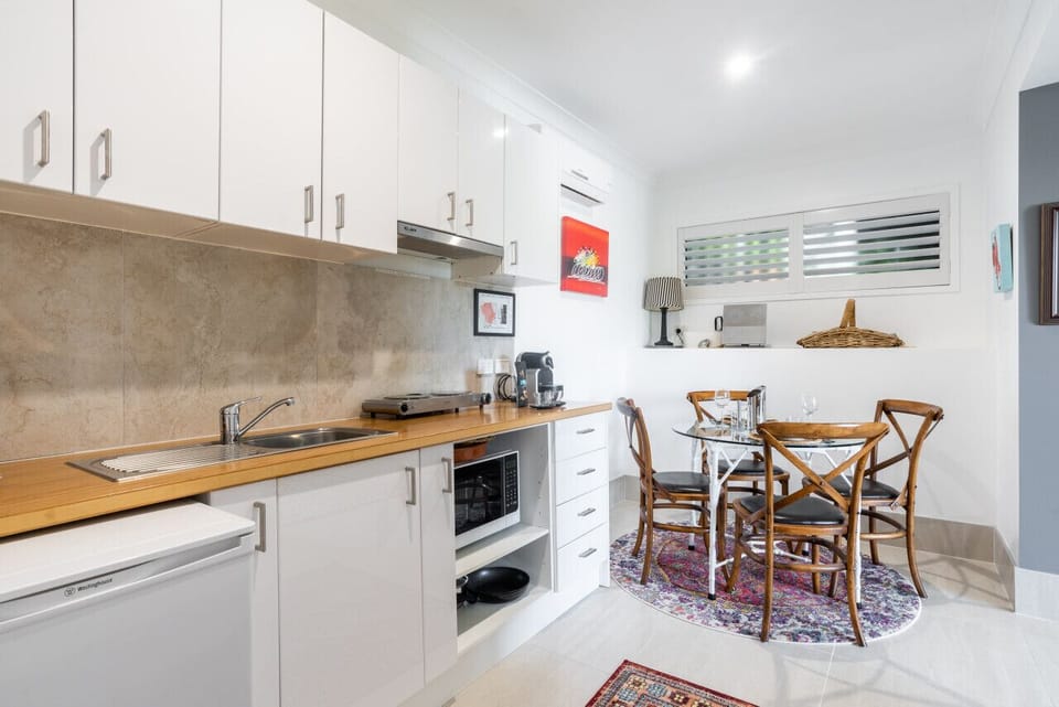 Compact kitchen with wooden countertops and a cozy dining area with a glass table.