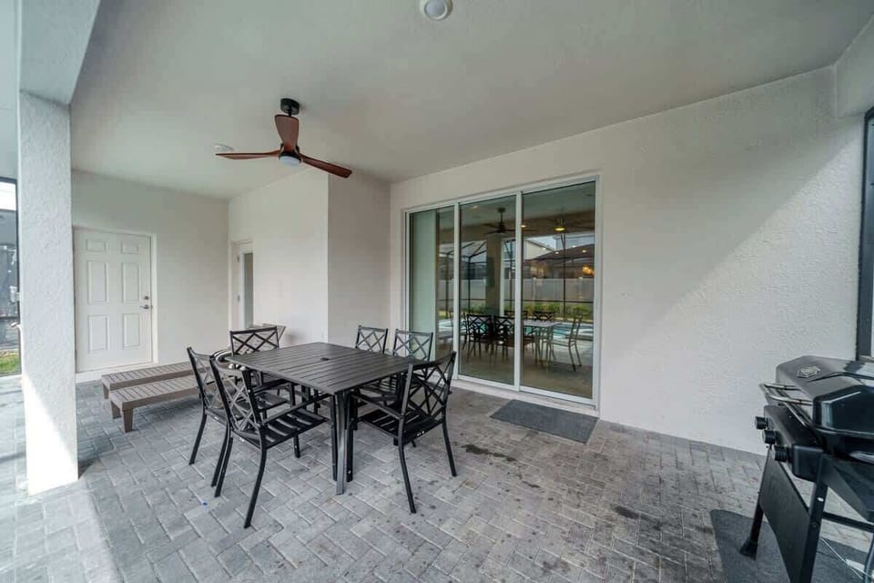 Covered patio w/ outdoor dining, ceiling fan, and grill setup for relaxed meals outside.