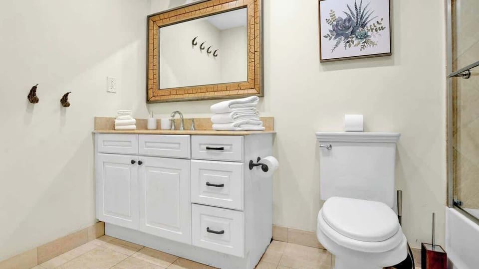 Spotless full bathroom stocked with fresh towels and basic essentials.