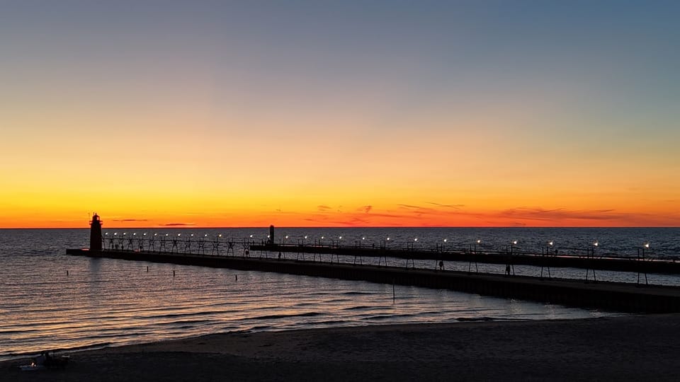 Drive 10 minutes and find yourself here — South Haven's lighthouse at golden hour, with Lake Michigan stretching to the horizon.
