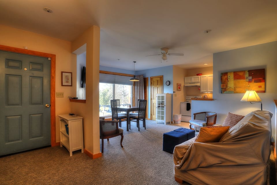 View of entry door, living room, and kitchen
