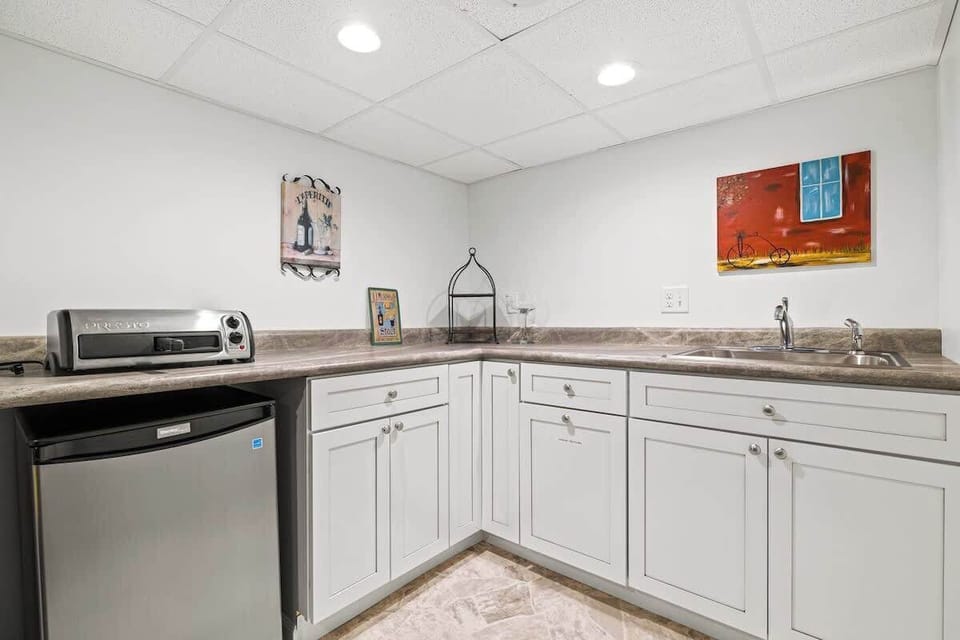 Lower level kitchen is complete with sink, mini fridge, and pizza maker. 