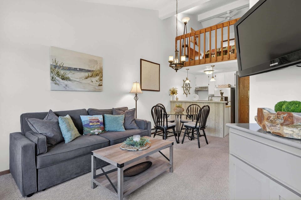 Living room-Relax in your cozy open-plan living space with plush seating, charming loft above, and modern kitchen ready for memorable meals.
