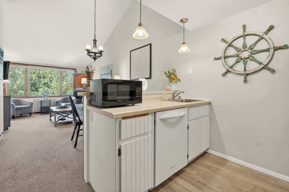 Your nautical-themed kitchenette makes meal prep a breeze with modern appliances and charming ship's wheel décor, perfectly complementing the bright living space.