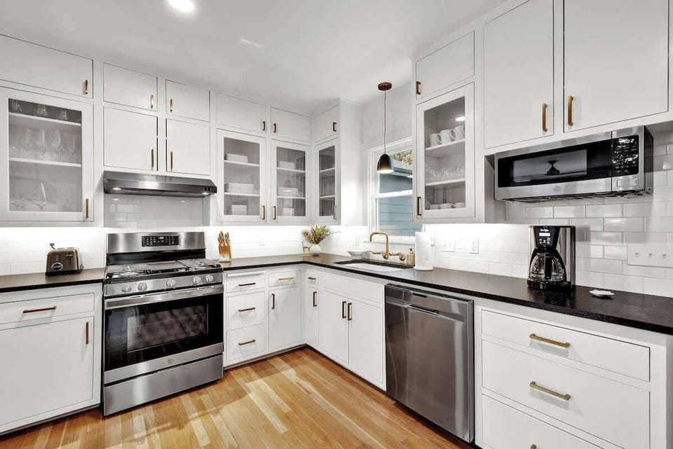 The kitchen boasts stunning bright white cabinets, sleek black countertops, and gleaming stainless steel appliances.
