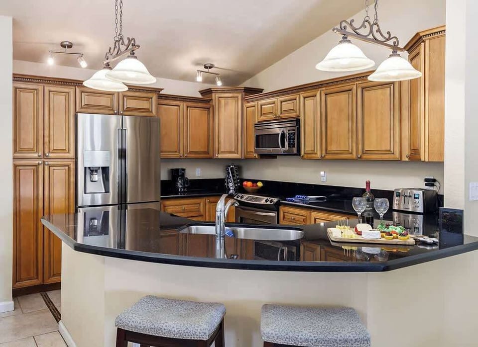 Fully equipped kitchen with stainless steel appliances, breakfast bar seating, and dining table with seating for 4 guests.