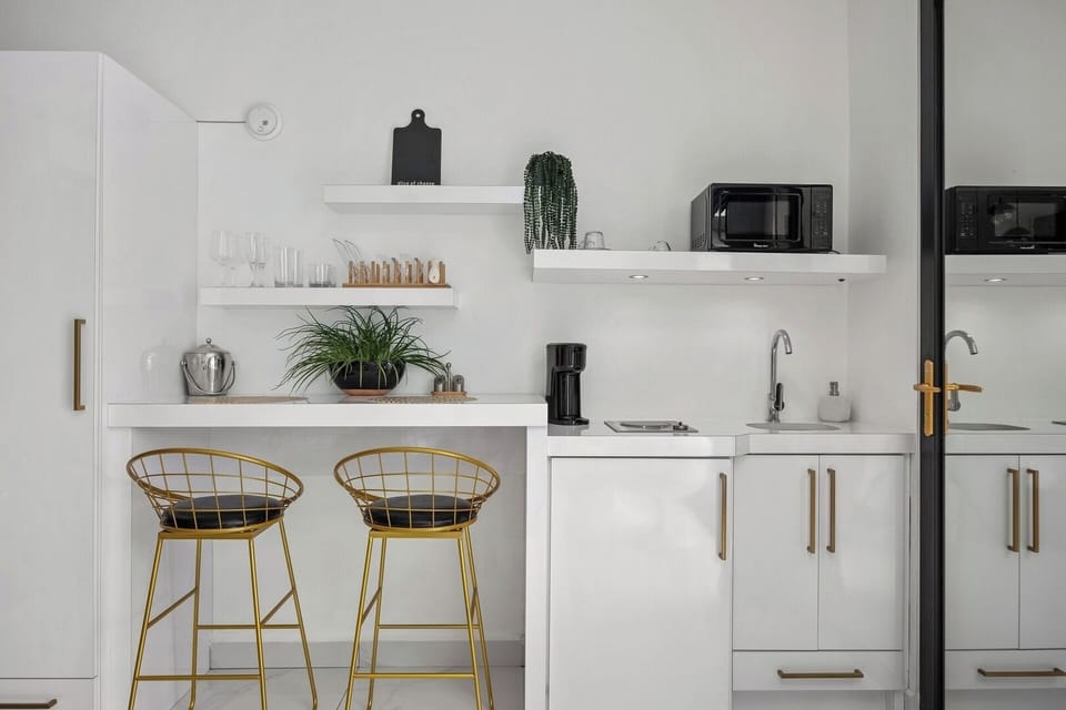 Kitchenette equipped with mini fridge, stovetop with one burner, microwave, coffee maker, coffee, sugar, creamer, dinnerware, silverware, pots and pans.
