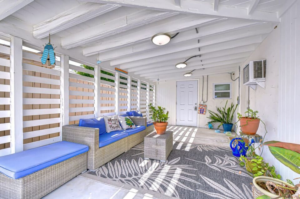 Unwind in this breezy, tropical-inspired outdoor lounge featuring cozy wicker seating, vibrant greenery, and cooling shade — perfect for morning coffee or evening cocktails in comfort and privacy.
