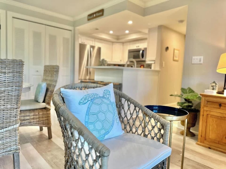 Cozy wicker seating with a coastal-themed pillow in a bright, modern living space.