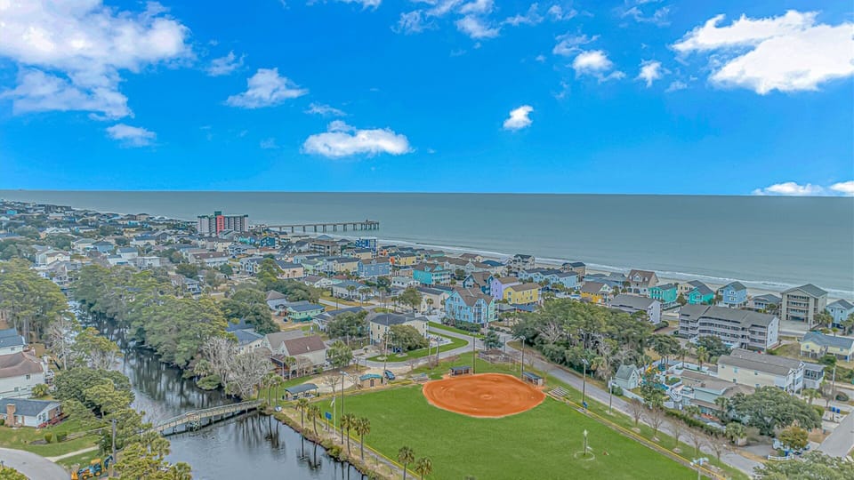 Aerial view of a charming coastal community with colorful homes, recreational facilities, and direct ocean access.