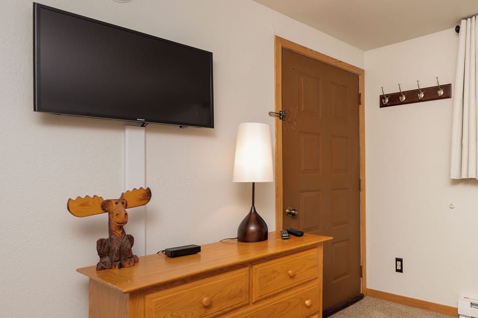 Unwind in your cozy retreat with wall-mounted TV, charming moose décor, and convenient storage for all your belongings.