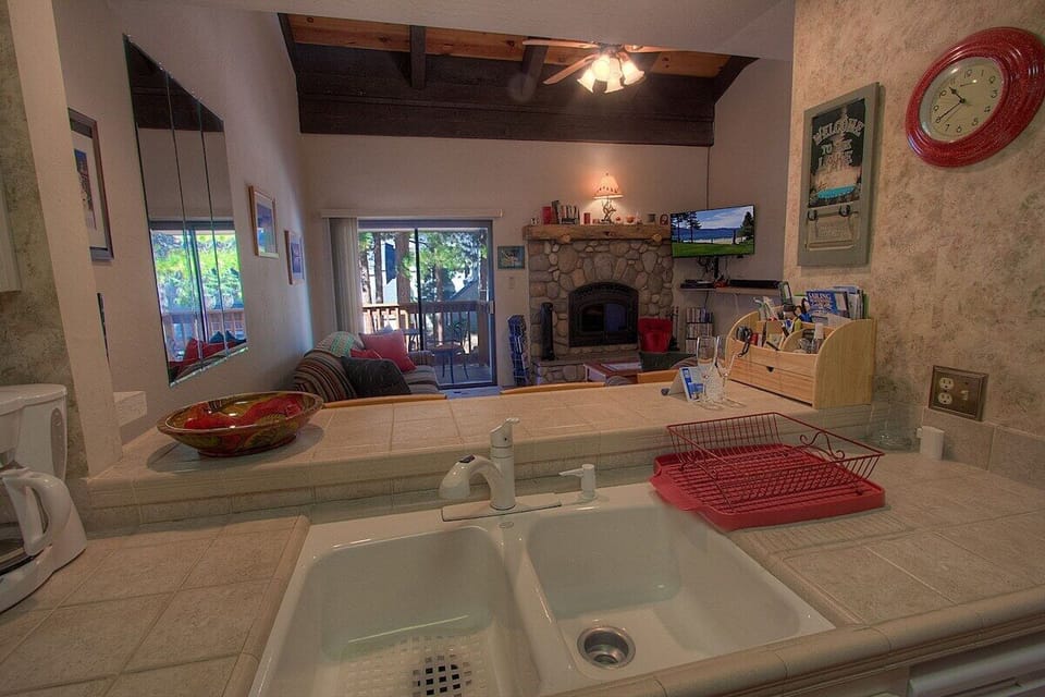 Kitchen sink area with counter, living room in view, fireplace in view, TV in view, sliding door in view, and balcony in view.