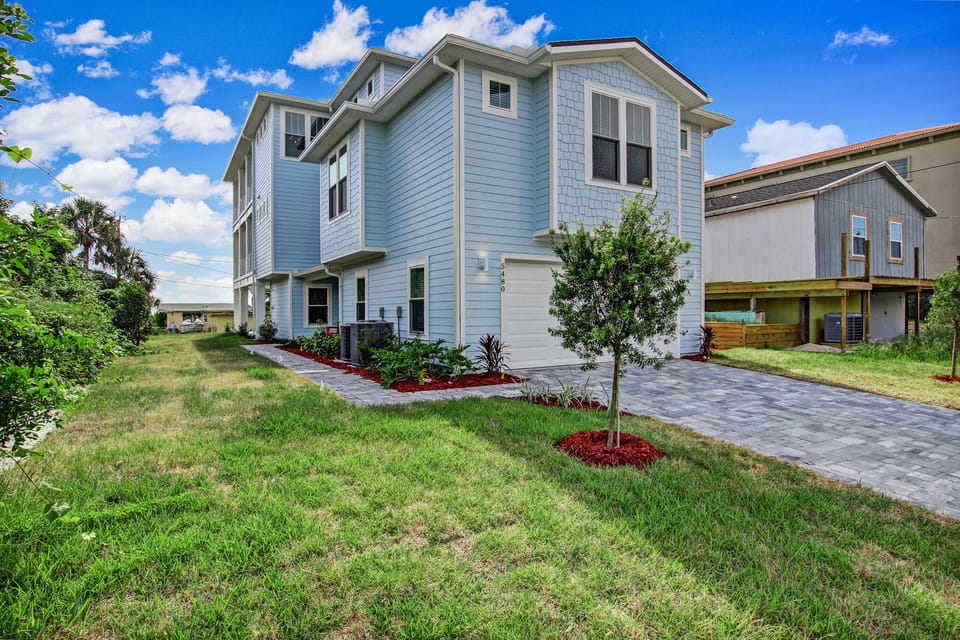 Charming coastal home with a private driveway and manicured front yard just steps from the beach.